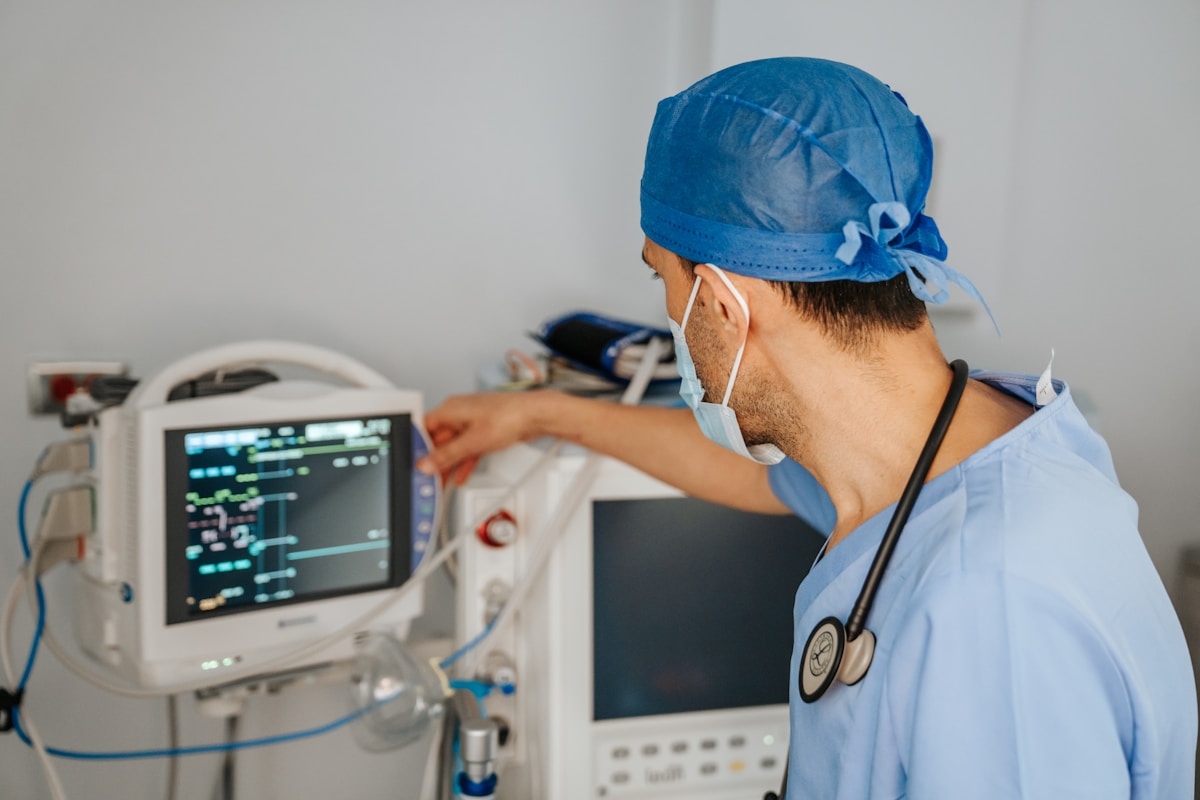 Profesional clínico inspeccionando un monitor de signos vitales en una sala de hospital luminosa
